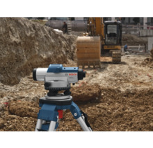 Stavenisko s nivelačným prístrojom na statíve a bagrom v pozadí