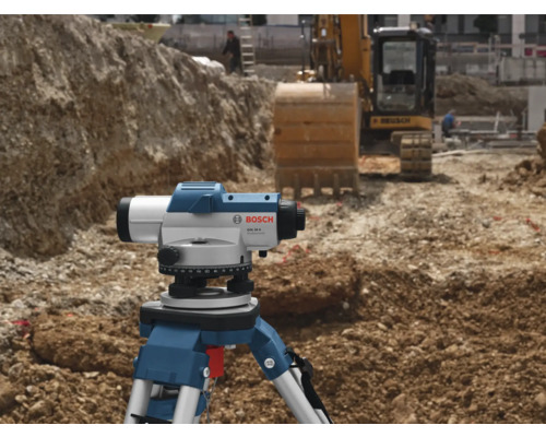 Stavenisko s nivelačným prístrojom na statíve a bagrom v pozadí