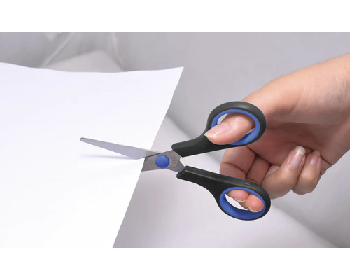Ruka strihá papier nožnicami.