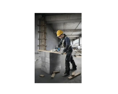 Remeselník s ochrannou helmou reže drevené dosky kotúčovou pílou.