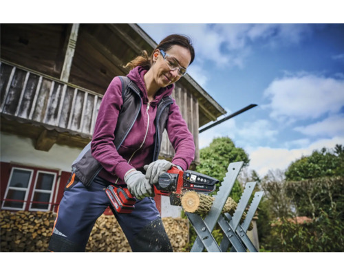 Žena reže kus dreva akumulátorovou pílou na kozlíku