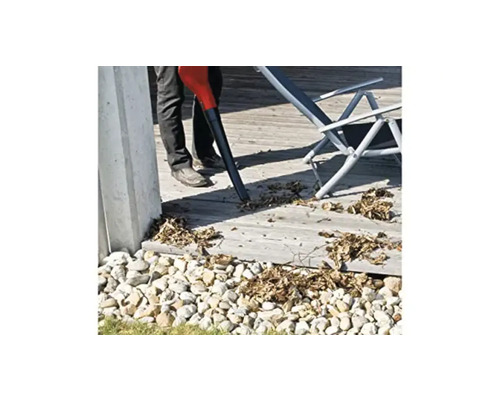 Osoba používa vysávač lístia na terase obklopenej kameňmi.