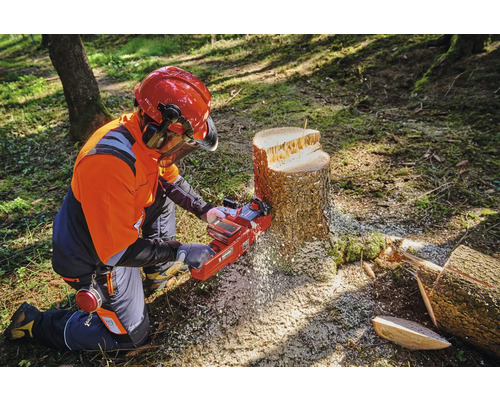 Osoba v ochrannom odeve používa reťazovú pílu na pni.
