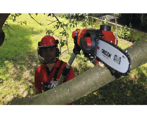 Muž s ochrannou prilbou reže konár pomocou tyčovej píly