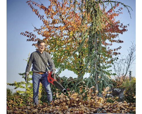 Muž používa fúkač lístia v záhrade na odstraňovanie lístia.