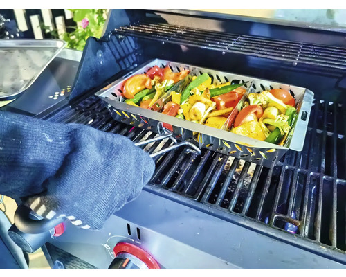 Zelenina v grilovacej panvici na grile, ktorú drží osoba v kuchynskej rukavici