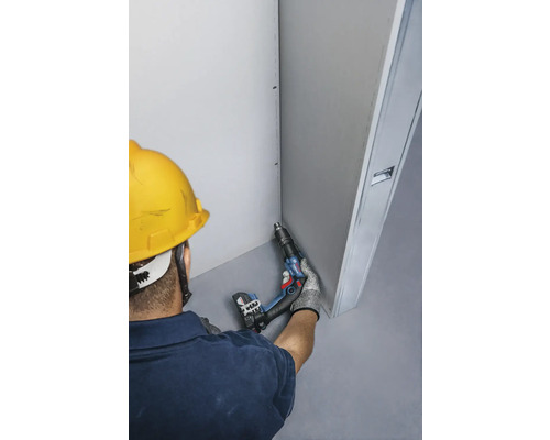 Remeselník s akumulátorovým skrutkovačom pri montáži sadrokartónu