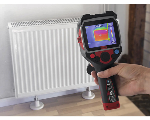 Ruka drží termokameru pred radiátorom na meranie teploty.