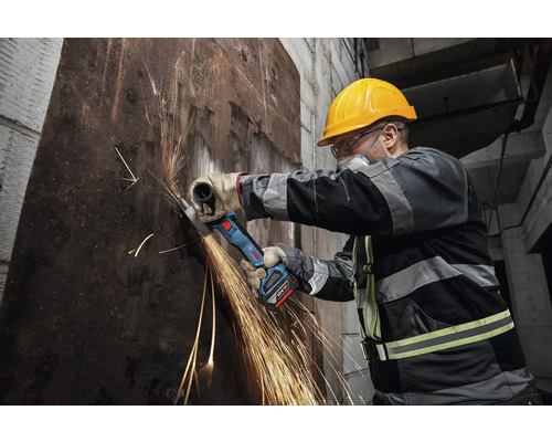 Robotník s akumulátorovou uhlovou brúskou reže kov