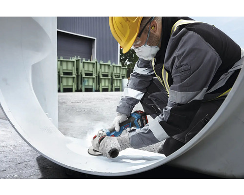 Stavebný robotník opracováva rúrku uhlovou brúskou