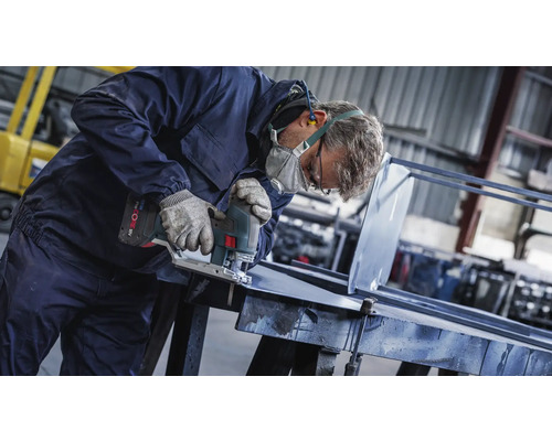 Remeselník reže kov priamočiarou pílou v dielni.