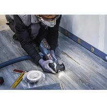 Remeselník používa multifunkčný nástroj na laminátovej podlahe na renováciu.