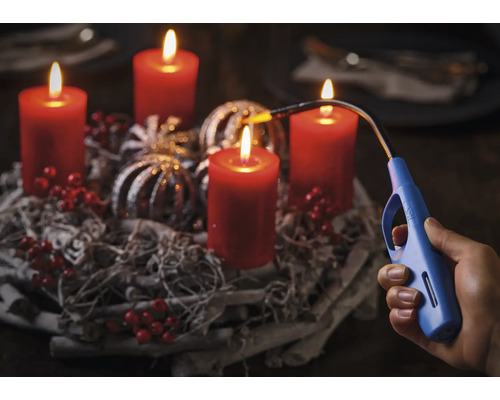 Adventný veniec so štyrmi horiacimi sviečkami a ruka so zapaľovačom