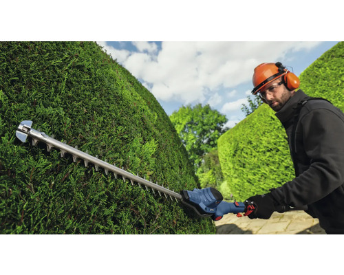 Osoba strihá živý plot pomocou nožníc na živý plot.