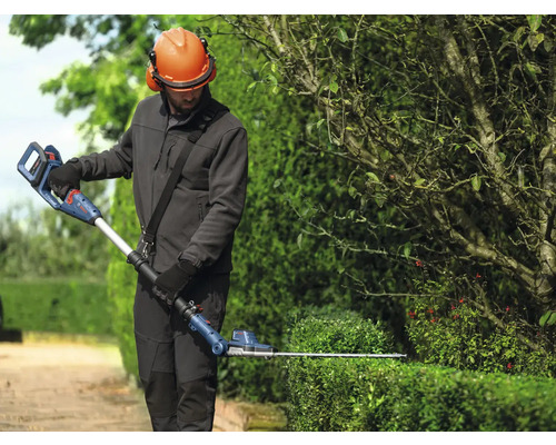 Osoba strihá živý plot pomocou akumulátorových teleskopických nožníc na živý plot Bosch.