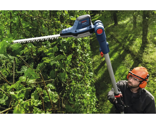 Osoba strihá živý plot pomocou akumulátorových teleskopických nožníc na živý plot Bosch