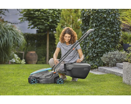 Žena kľačí v záhrade a montuje kosačku na trávu s 30-litrovým zberným košom.