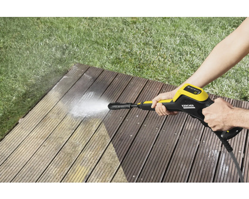 Osoba čistí drevenú terasu pomocou vysokotlakového čističa Kärcher.