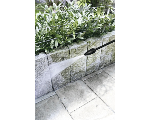 Vysokotlakový čistič sa používa na čistenie kamennej steny v záhrade.