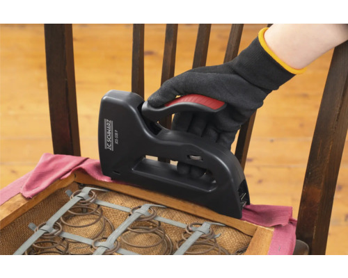 Ruka v rukavici používa sponkovačku na prečalúnenie stoličky.