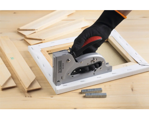 Ruka v rukavici používa ručnú zošívačku na plátne