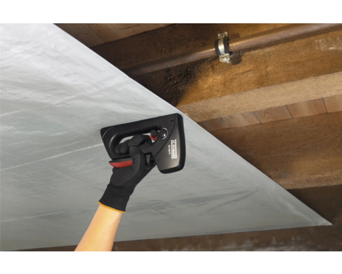 Osoba pripevňuje parozábranu ručnou sponkovačkou na drevený strop.