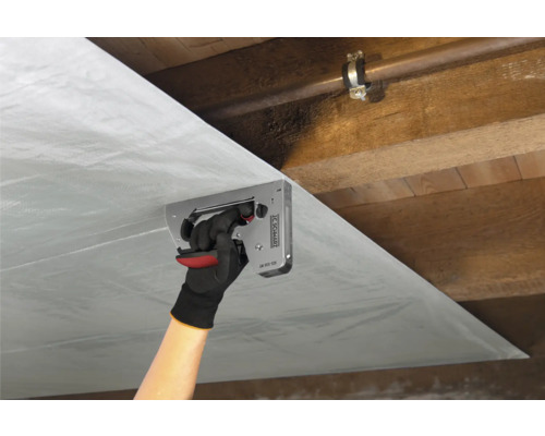 Osoba pripevňuje parozábranu sponkovačkou k drevenému stropu.