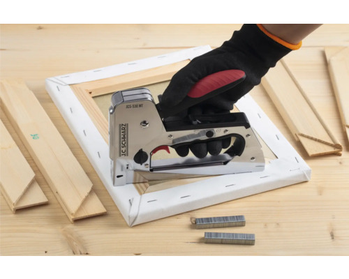 Ruka s zošívačkou na ráme plátna