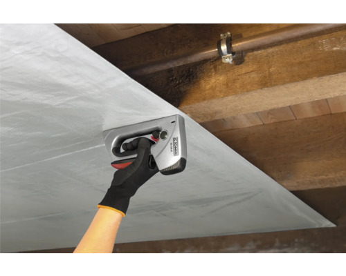 Osoba pripevňuje fóliu ručnou sponkovačkou na drevený strop.