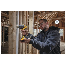 Remeselník vŕta vŕtačkou Dewalt do dreva v hrubej stavbe.