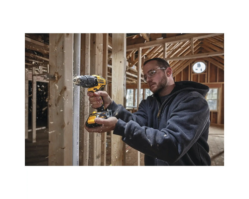 Remeselník vŕta vŕtačkou Dewalt do dreva v hrubej stavbe.