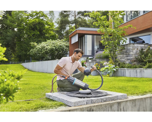 Muž používa sudové čerpadlo Gardena v záhrade na zavlažovanie záhrady.