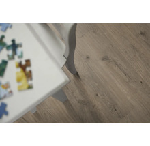Detail laminátovej podlahy s dreveným vzhľadom a bielej nohy stola