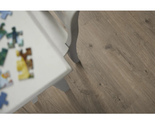 Detail laminátovej podlahy s dreveným vzhľadom a bielej nohy stola