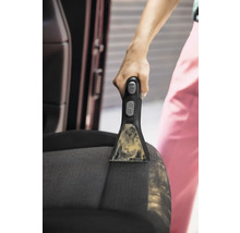 Detailný záber osoby čistiacej autosedačku pomocou prenosného čističa škvŕn.