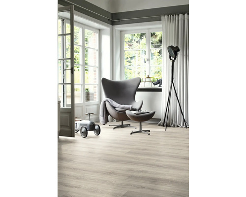 Svetlá obývacia izba s kreslom, stojacou lampou, drevenou podlahou a veľkým oknom