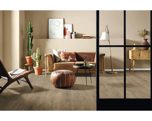 Obývacia izba s pohovkou, kreslom, stolom, stojacou lampou, komodou, dekoráciou a izbovými rastlinami na drevenej podlahe.