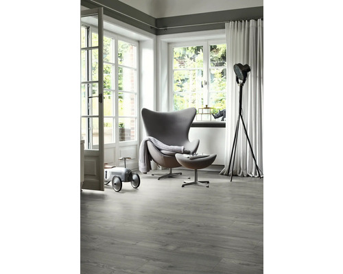 Svetlá miestnosť s moderným kreslom, stojacou lampou a sivou vinylovou podlahou s dreveným vzhľadom