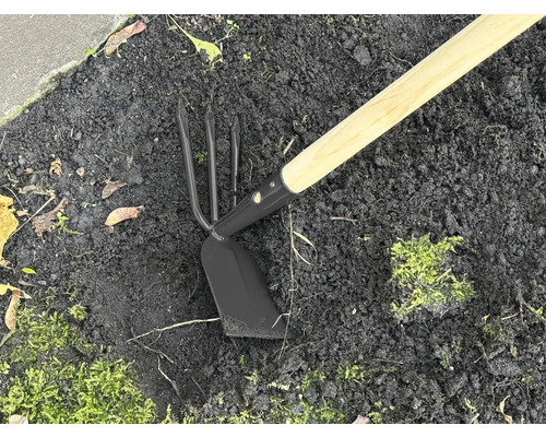 Záhradné náradie s drevenou násadou a kovovou hlavou v zemi