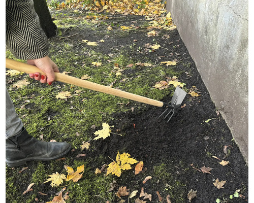 Práca na záhrade s kombinovanou motykou na spracovanie pôdy