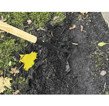 Záhradná motyka s drevenou rukoväťou používaná na tmavej zemi