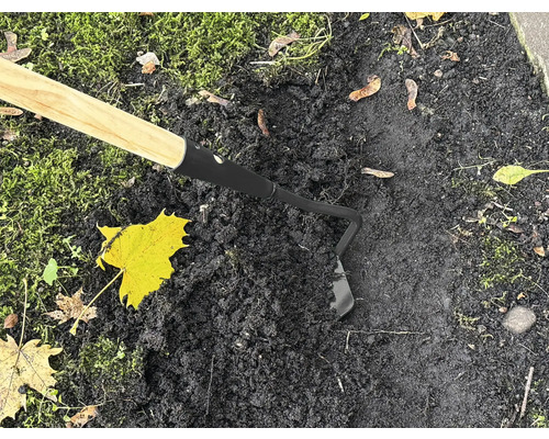 Záhradná motyka s drevenou rukoväťou používaná na tmavej zemi