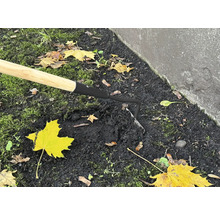 Detailný záber motyky s drevenou rukoväťou v záhradnej pôde.