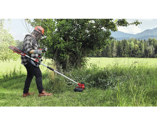 Osoba obsluhujúca akumulátorový vyžínač v trávnatom vonkajšom prostredí.