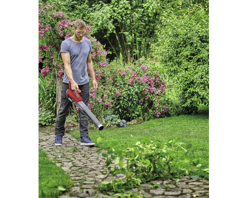 Muž používa na záhrade vysávač lístia na odstránenie lístia a záhradného odpadu.