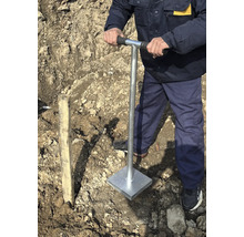 Muž zhutňuje pôdu ručným ubíjadlom