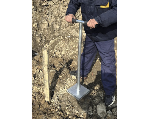 Muž zhutňuje pôdu ručným ubíjadlom