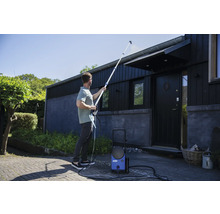 Muž čistí strechu domu vysokotlakovým čističom