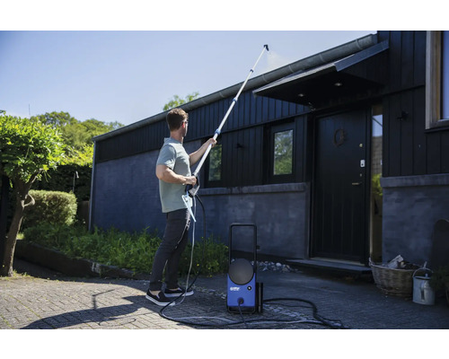 Muž čistí strechu domu vysokotlakovým čističom