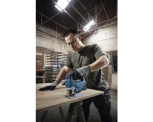 Muž reže drevenú dosku priamočiarou pílou Bosch